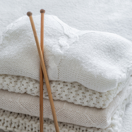 White sweaters and yarn for knitting close up. Knitting needles. Concept Handicraft.の写真素材