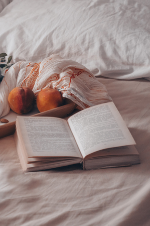 Breakfast in bed, a tray of tea, croissants, fruit, flowers. Morning. Cozy Apartment. Open the book the text is out of focus. Background layout. a day offの写真素材