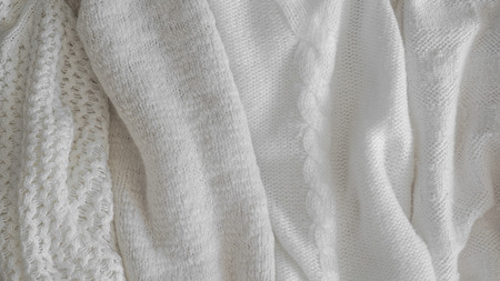 Warm knitted sweaters. Pile of knitted clothes on warm background, sweaters, knitwear, space for text, Autumn winter concept.の写真素材