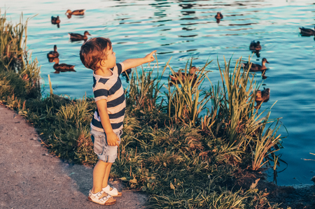 Happy child, little boy looks down, pensive look and holding in hands the growths outdoors. Space for Your Text. Retro toned. Summertimeの写真素材