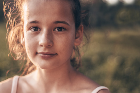 Portrait of pretty beautiful young girl in the evening sunshine in nature. girl enjoying summer and sunny weather on the meadow.の写真素材
