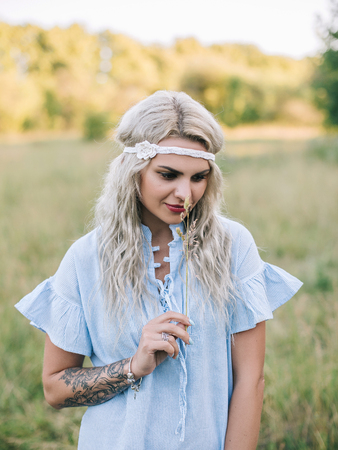 Portrait of a beautiful girl in a blue dress with a headache in a field at sunset in summer. Casual summer clothes. Close-up.の写真素材