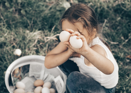 Little girl holding and picking good eggs quality organic and bring to the eye on the farm. The only...