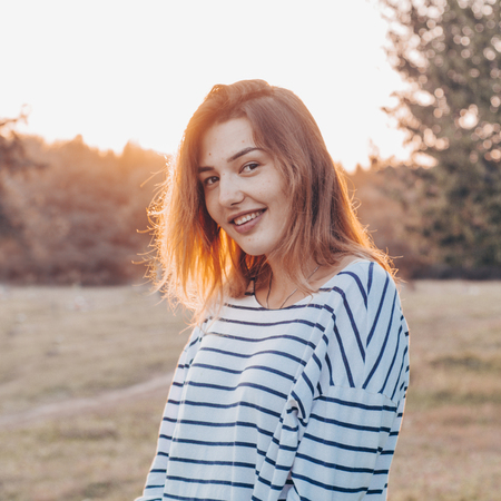 Young woman relaxing in summer sunset sky outdoor. People freedom style. Fashion Lifestyle, Portrait of Beautiful Young Woman Backlit at Sunset Outdoors. Soft warm sunny colors.の写真素材