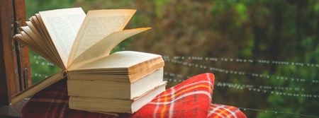 Cozy autumn still life: cup of hot coffee and opened book on vintage windowsill with red blanket, pumpkin, pine cone, candles and rain outside. Autumn. Apartment. Rainの写真素材
