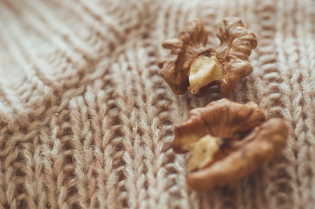 Walnuts in sweaters. Walnut kernels in a bowl and whole walnuts. Cozy autumn or winter concept.
