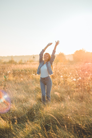 Autumn Girl enjoying nature on the field. Beauty Girl Outdoors raising hands in sunlight rays. Beautiful Teenage Model girl in white dress running on the Field, Sun Light. Glow Sun. Free Happy Womanの写真素材