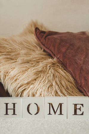 Still life details in home interior of living room and the inscription HOME. A lot of decorative cozy pillows. Rest. Cozy autumn or winter concept, knitwear. HOME conceptの写真素材