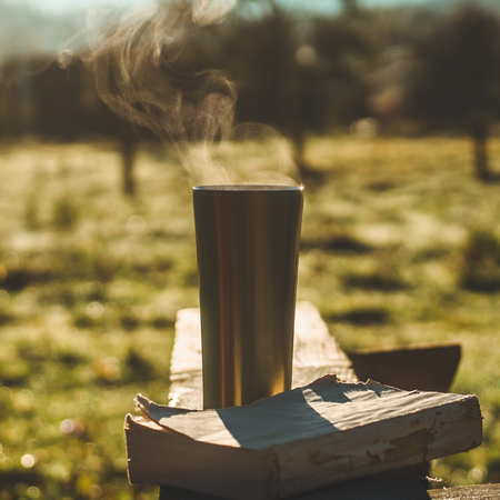 Breakfast with a book in the open air, warm blanket, Steam over a thermo cup. Open book on nature. Book and drinking coffee. Reading at outdoorの写真素材