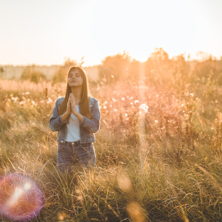 girl closed her eyes, praying outdoors, Hands folded in prayer concept for faith, spirituality and religion. Peace, hope, dreams concept.の写真素材