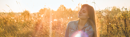 Autumn Girl enjoying nature on the field. Beauty Girl Outdoors raising hands in sunlight rays....