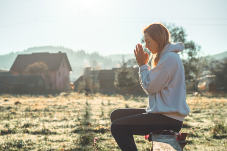In the morning Girl closed her eyes, praying outdoors, Hands folded in prayer concept for faith, spirituality and religion. Peace, hope, dreams concept.の写真素材