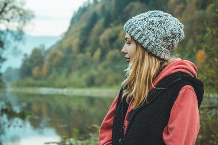 Portrait of young hipster girl enjoying an amazing view of mountains, pretty female traveler looking at the sky, standing at place.の写真素材