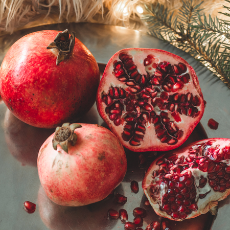 Cozy winter morning at home with fruits. Fruit Pomegranate in a winter composition, Christmas trees, candles, cones in a jar on the background. Symbol of New Year and Christmasの写真素材
