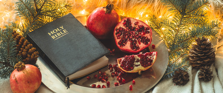Fruits and vegetables for harvesting. Still life - bible and pomegranate on an iron plate in the branches of the Christmas treeの写真素材
