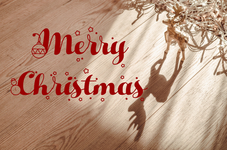 Merry christmas text sign on reindeer ornaments with greeting card and fir branches and cones on rustic wooden background. space for text. top view. seasonal greetings concept. winter holidaysの写真素材