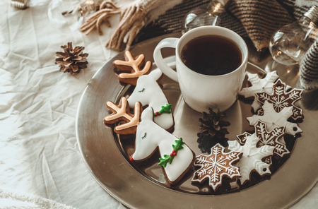 cup with tea or coffee, fir branch, Christmas cookies in the shape of snowflakes, cozy knitted...