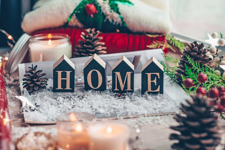 Concept of Home and comfort. Christmas decor Warm sweater, candles, led string lights and Christmas tree. Word Home. Winter mood, Cozy Home, holiday decoration.の写真素材