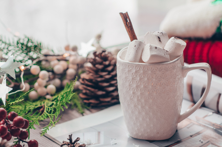 Christmas decor: Warm sweater, cup of hot cocoa with marshmallow and cinnamon stick, ginger christmas cookies, led string lights, candy, candles and Christmas tree. Winter mood, holiday decoration.の写真素材