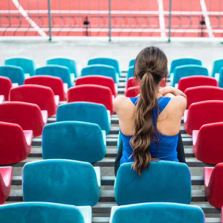 Fitness sport woman in fashion sportswear, sits looking at running sports girls, fitness exercise in the city street in the background of the stadium. Healthy lifestyle concept.の写真素材