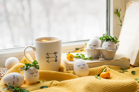 Happy Easter card. Cute Easter eggs with a painted face in a spring wreath, cup tea with kumquat. Happy easter.の写真素材