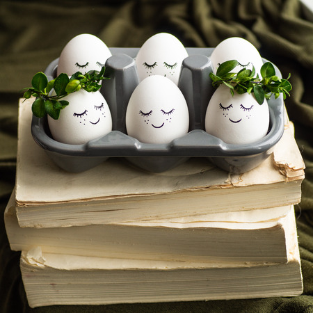 Happy Easter card. Cute Easter eggs with a painted face in a spring wreath with copy space for text....