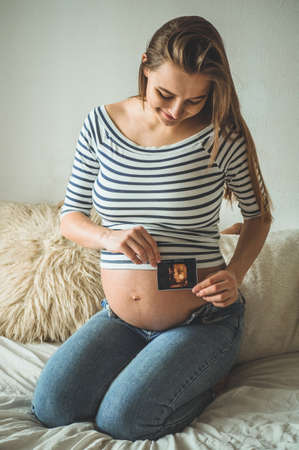 Pregnant woman holding ultrasound image. Concept of pregnancy, health care, gynecology, medicine....