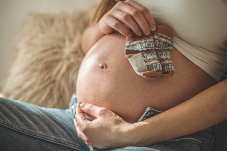 Beautiful pregnant woman holds small child clothes. Happiness. Concept of pregnancyの写真素材