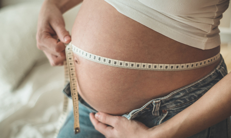 Happy pregnant woman with measuring tape Pregnancy, maternity, preparation and expectation concept. Space for textの写真素材