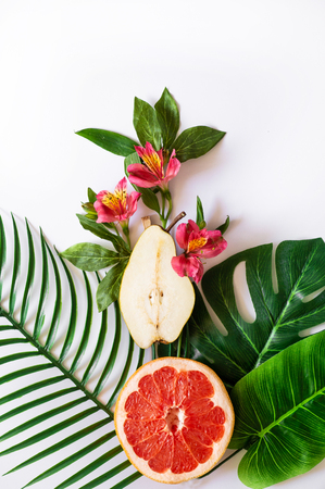 Summer tropical theme background or template with a space for a text, various fruits, green leaves and flowers. Bright summer backgroundの写真素材