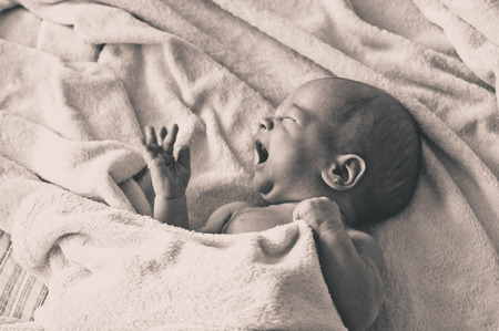Crying hungry newborn baby lying on the bed. Love baby. Newborn baby and mother.の写真素材