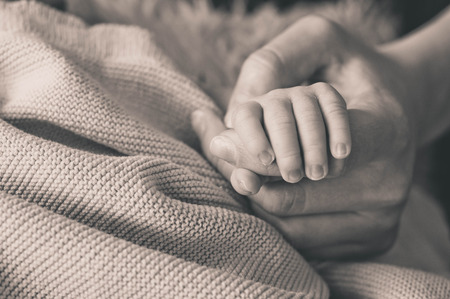 Female hand holding her newborn baby hand. Mom with her child. Maternity, family, birth concept. Copy space for your text.の写真素材