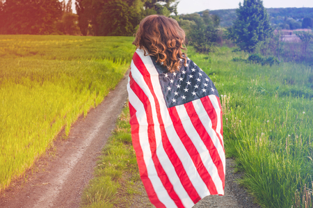 Happy women running in the field with American flag USA celebrate 4th of July.の写真素材