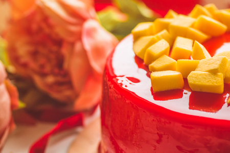 Birthday cake with one candle and red frosting. National bakery. Round cake with mango.の写真素材