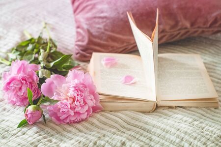 Still life details in home interior of living room. Cup of tea with Pions flowers and spring decor on the books. Read, Rest. Cozy spring concept.の写真素材
