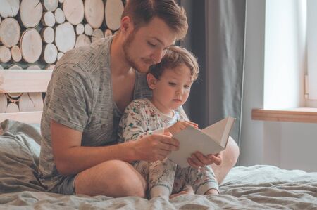 Dad and Son read a book together, smiling and hugging. Family holiday and togetherness. Happy father day!の写真素材