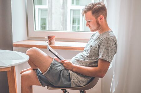 Technology, home - lifestyle concept close up of man working with the tablet computer and sitting on...