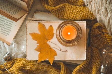 Sweet Home. Still life details in home interior of living room. Sweaters and candle,  autumn decor on the books. Read, Rest. Cozy autumn or winter concept.の写真素材