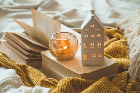 Sweet Home. Still life details in home interior of living room. Sweaters and candle,  autumn decor on the books. Read, Rest. Cozy autumn or winter concept.の写真素材