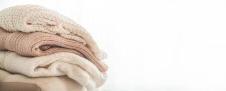 A stack of knitted sweaters in the interior of the living room. The concept of autumn winter comfort