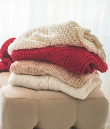 A stack of knitted sweaters in the interior of the living room. The concept of autumn winter comfortの写真素材