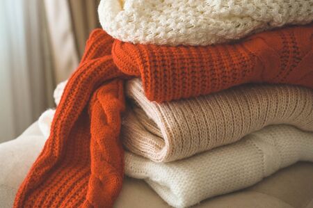 A stack of knitted sweaters in the interior of the living room. The concept of autumn winter comfortの写真素材