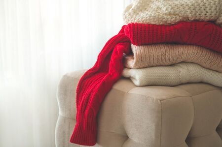 A stack of knitted sweaters in the interior of the living room. The concept of autumn winter comfortの写真素材