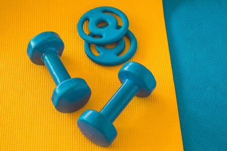 Water, sports blue dumbbells at karemat in the gym. Sport accessories. Sport equipment top view background. Sportswear and fashion. Sport equipment top viewの写真素材