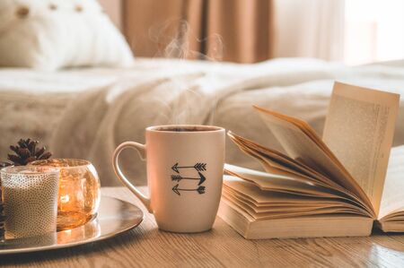 Book, cup of coffee and many candles on the home background.  Home and home decor. Candles flame. HOME conceptの写真素材