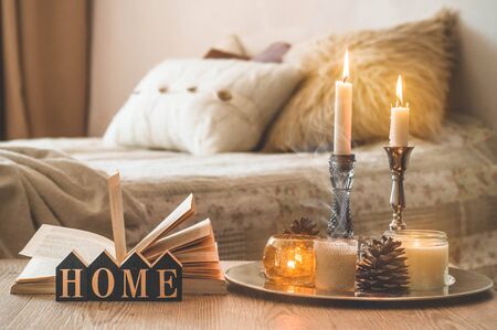 Book, cup of coffee and many candles on the home background.  Home and home decor. Candles flame. HOME conceptの写真素材