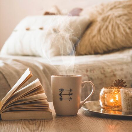 Book, cup of coffee and many candles on the home background.  Home and home decor. Candles flame. HOME conceptの写真素材
