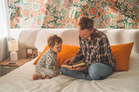Dad and Son read a book together, smiling and hugging. Family holiday and togetherness. Happy fathers day.の写真素材