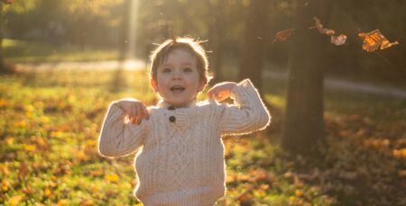 Happy little child baby boy laughing and playing in the autumn on the nature walk outdoorsの写真素材
