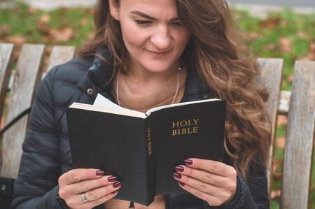 Women in outdoors reading Bible. Concept for faith, spirituality and religion. Peace, hopeの写真素材